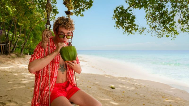 Man on the beach with a coconut
