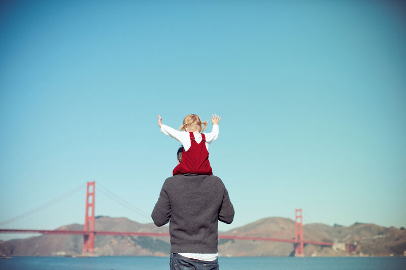 Kid on man's shoulders in front of the Golden Gate Bridge